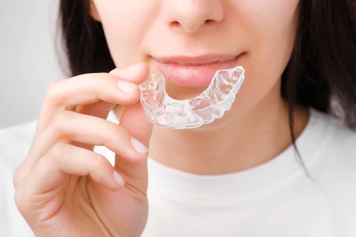 Close up of a young woman adjusting transparent clear teeth aligners
