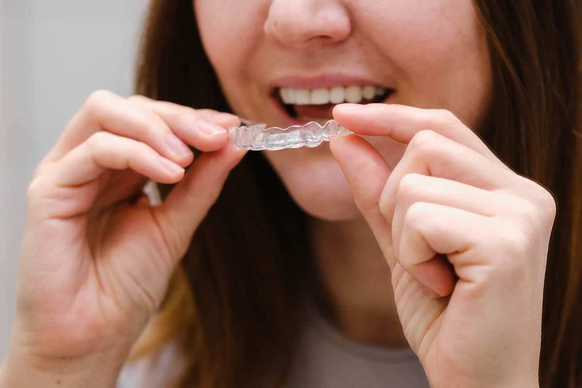 woman putting on her clear aligners