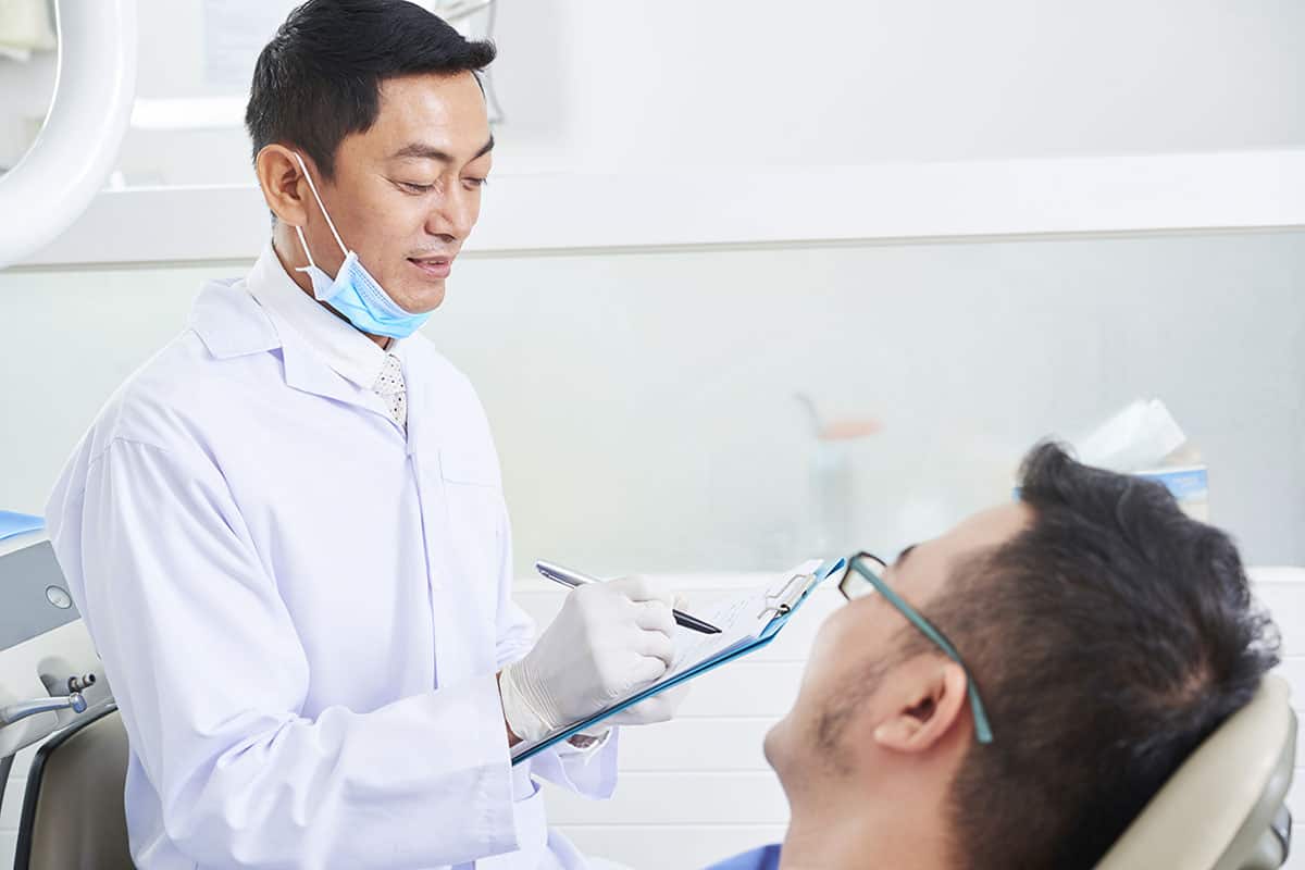 male dentist consulting young man in dentist's office
