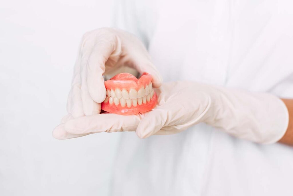  Dentist holding ceramic dental bridge